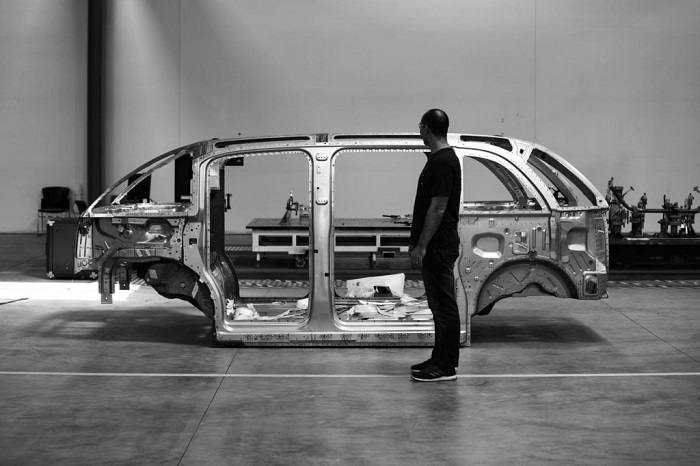 A Man Standing Behind The Car frame structure on automobile manufacturing and transportation line